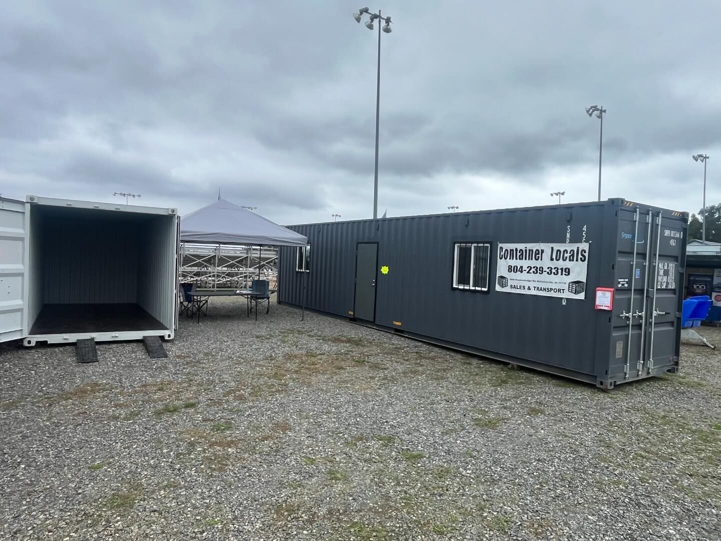 A row of shipping containers are sitting in a gravel lot.