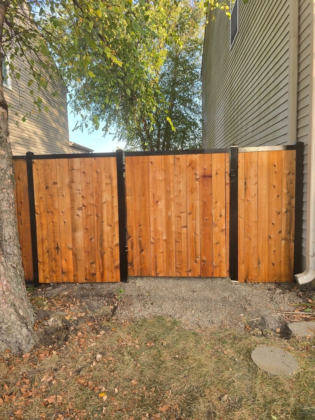 White picket fence in front of a gray house with a sidewalk and green lawn