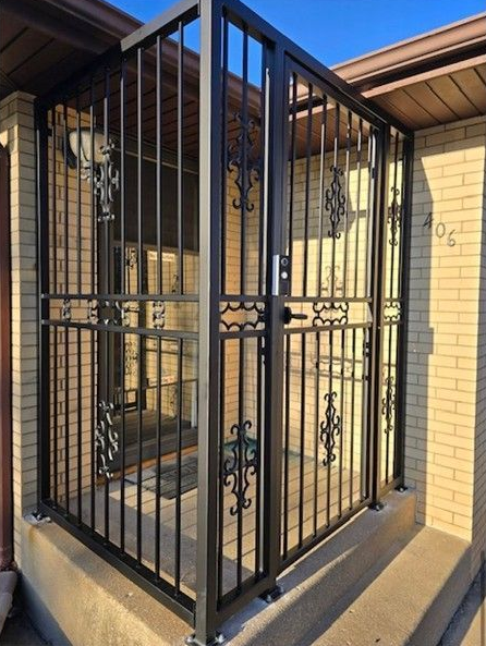 Black metal security cage enclosing a front porch entry beside a tan brick wall.