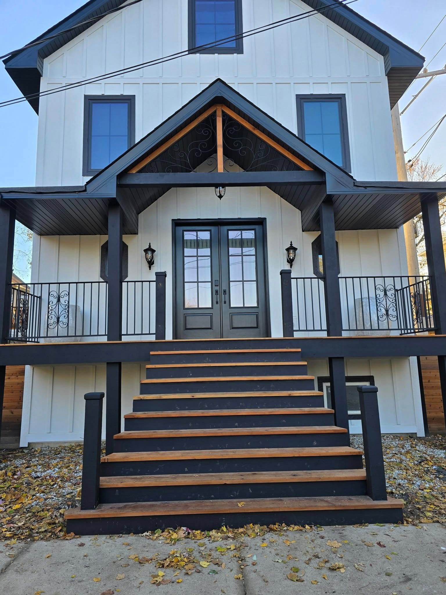 Front view of a white house with a covered porch and central staircase with black railings