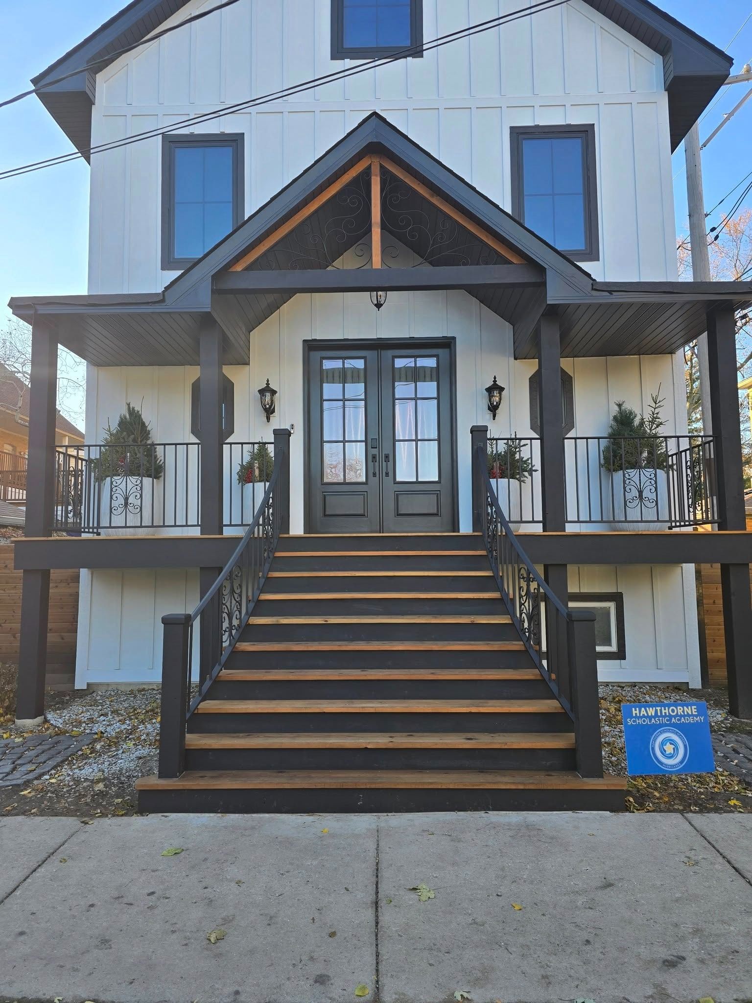 Front view of a white house with black trim and a central staircase leading to a covered porch