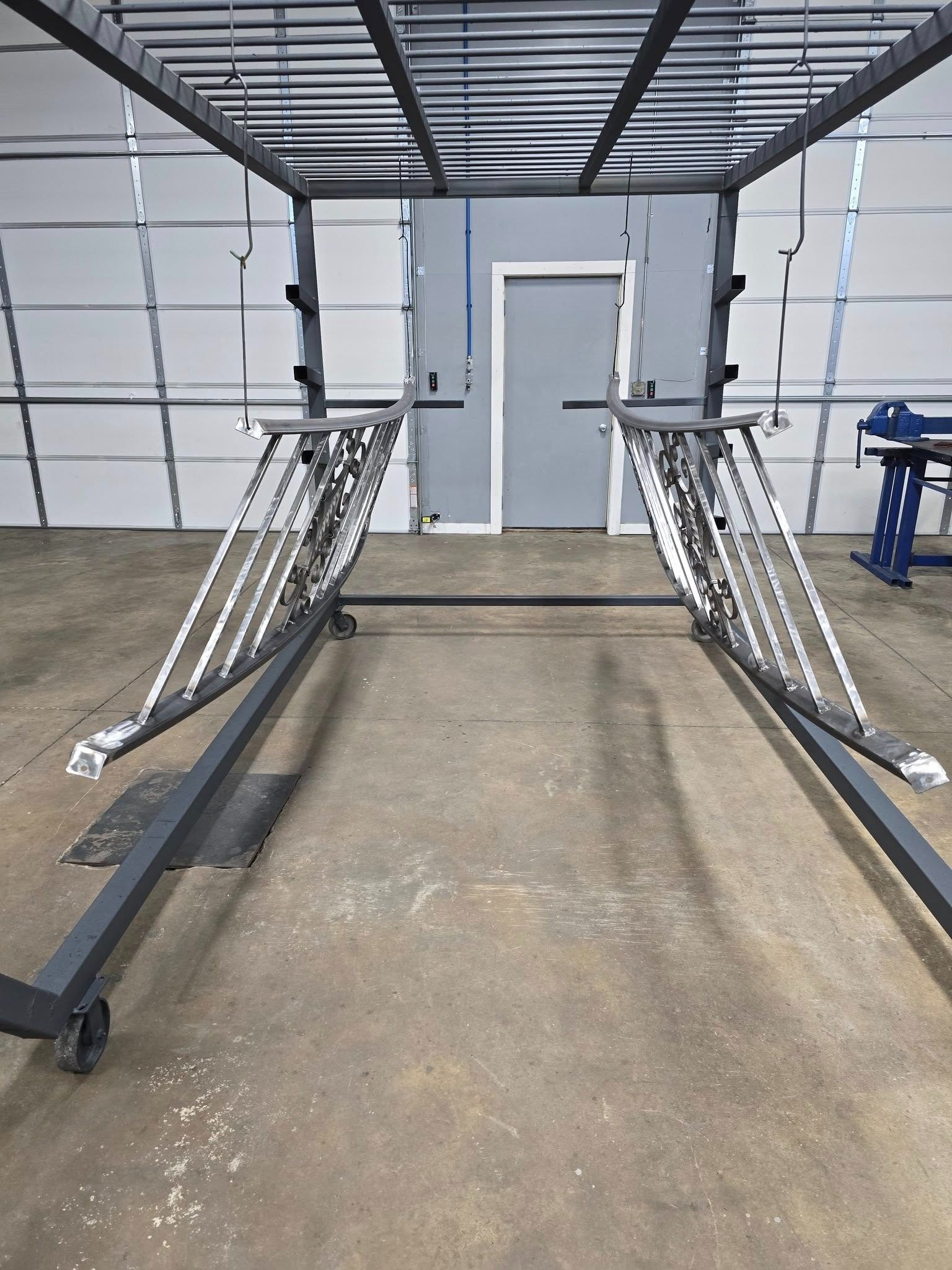 Indoor garage with two metal ramps leading to a white door on a concrete floor