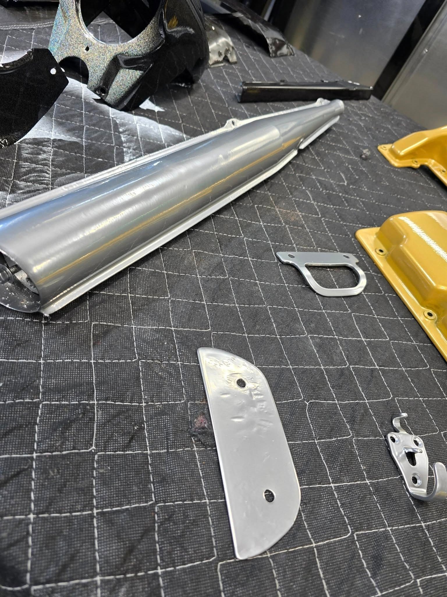Metal cones and cut sheet pieces on a workbench with a grid mat and yellow tools.
