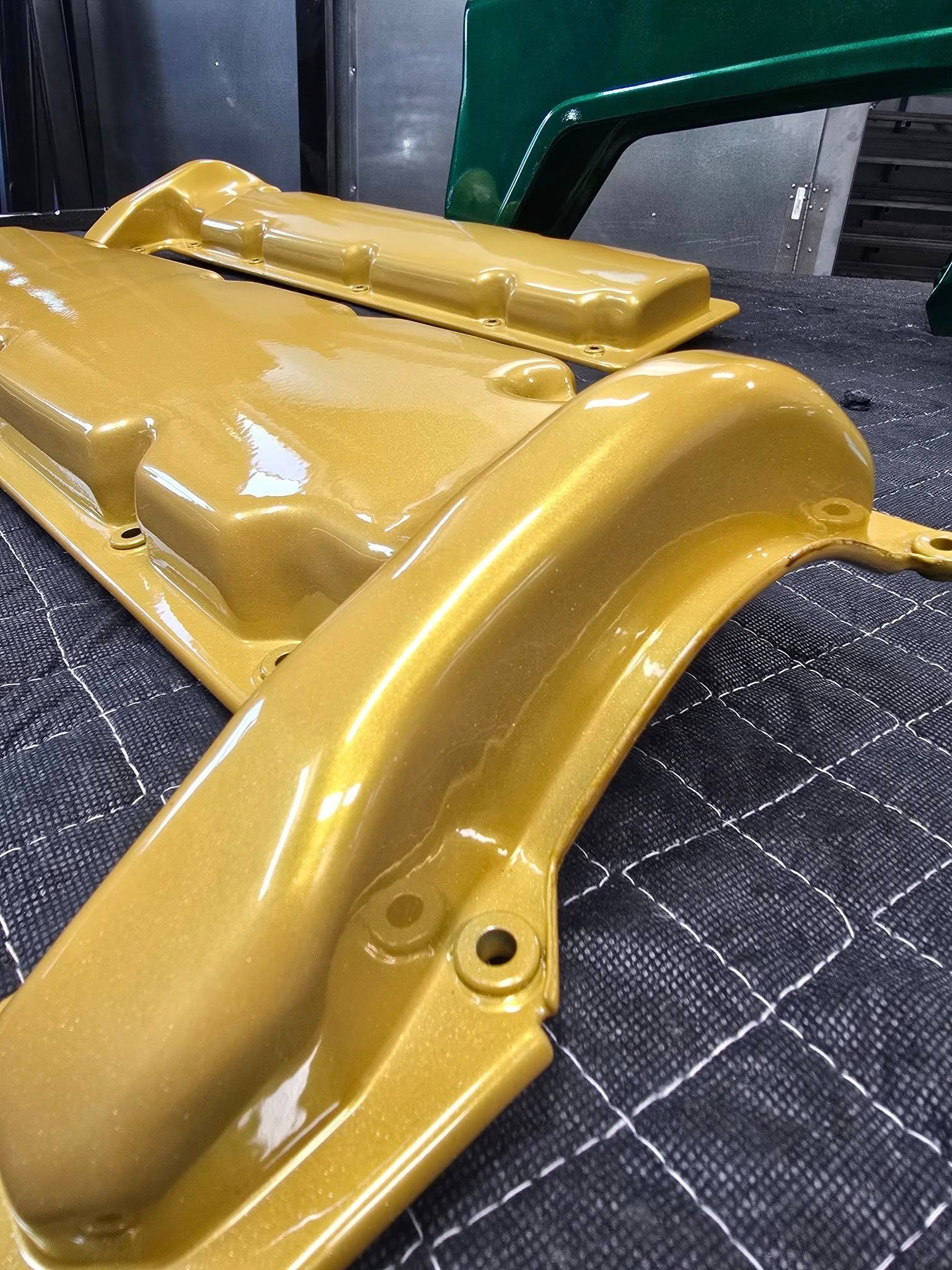 Close-up of a gold-painted car bumper resting on a dark quilted surface.