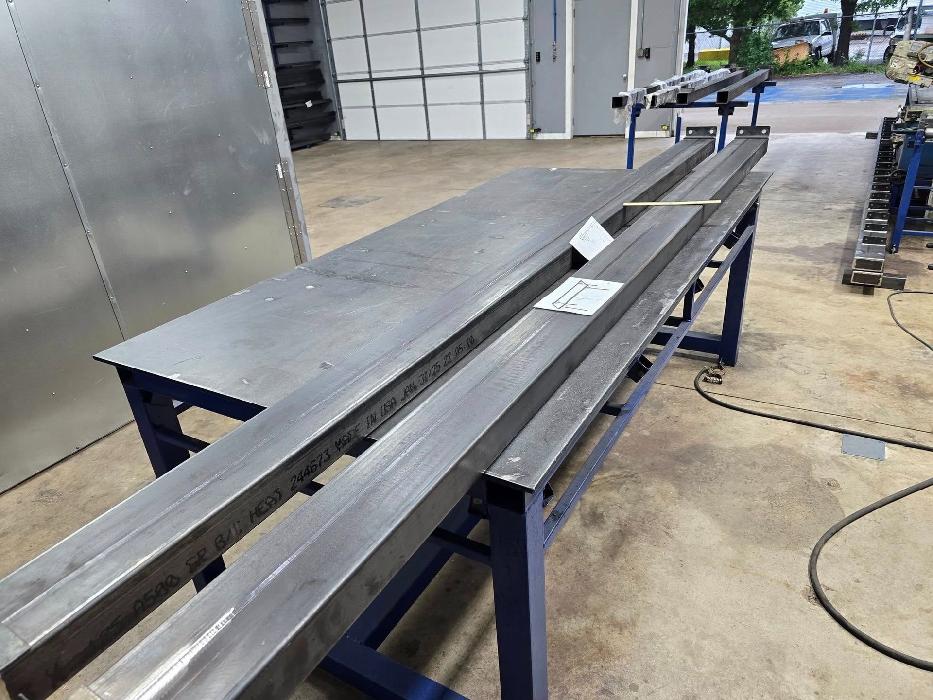 Industrial metal workbench with long steel beams in a workshop garage setting
