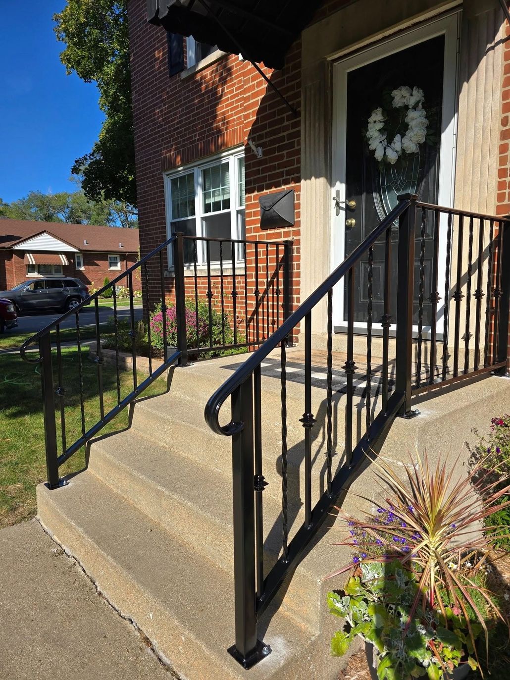 Front porch of a house with white railings, beige siding, and a staircase leading up to it
