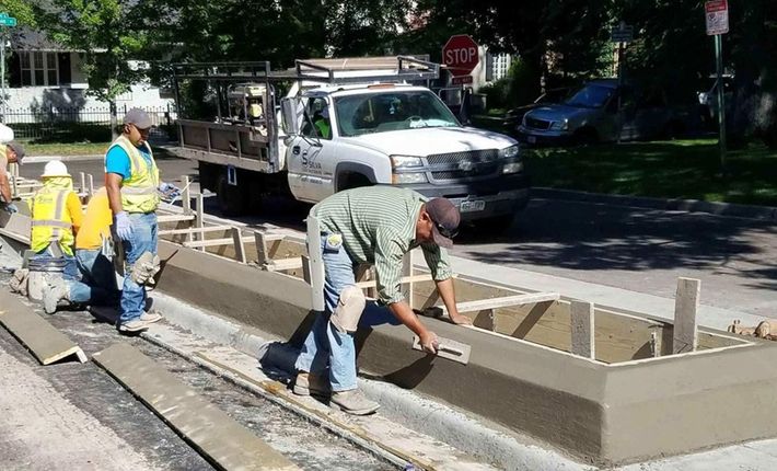 A group of construction workers are working on a sidewalk