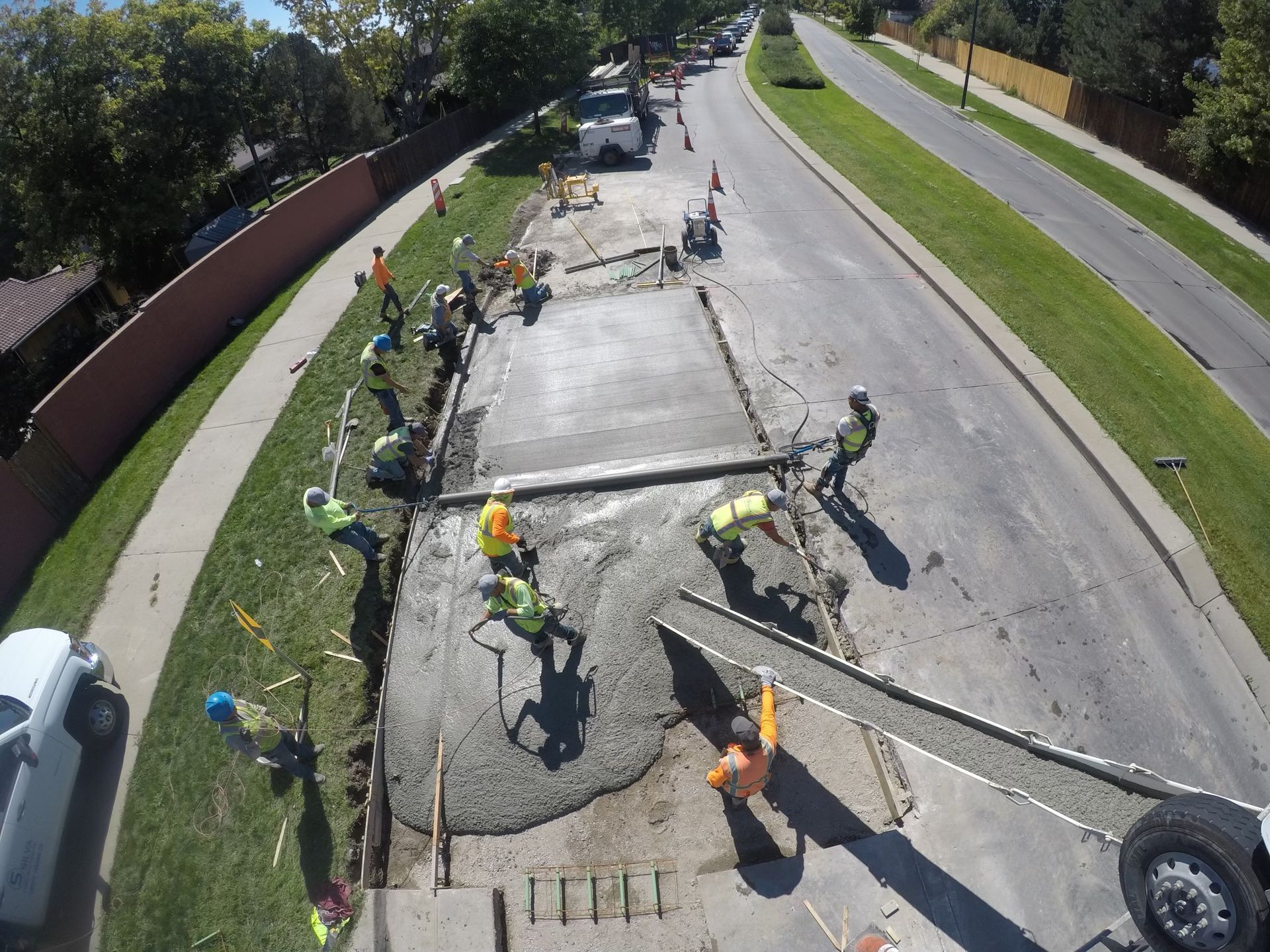 A group of construction workers are pouring concrete on the side of a road