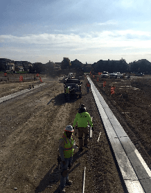 A group of construction workers are walking down a dirt road.