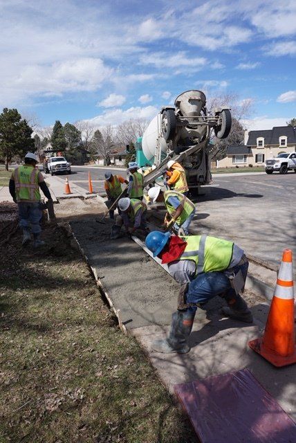 A group of construction workers are working on a sidewalk.
