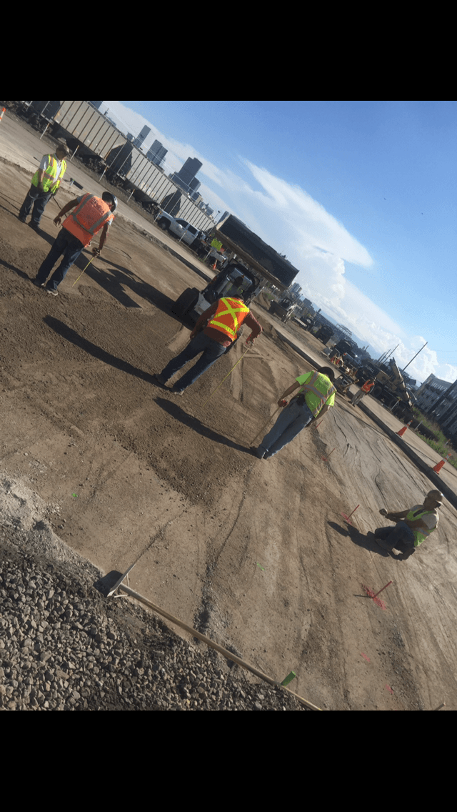 A group of construction workers are working on a dirt road.