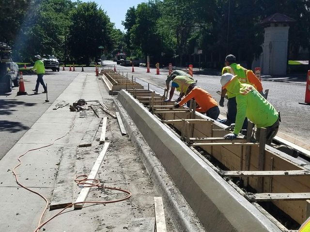 A group of construction workers are working on a sidewalk
