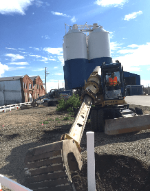 An excavator is digging a hole in the ground in front of a building.