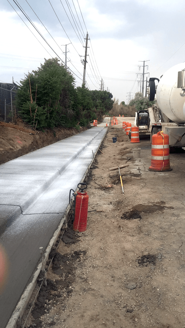 A concrete truck is pouring concrete on a sidewalk.