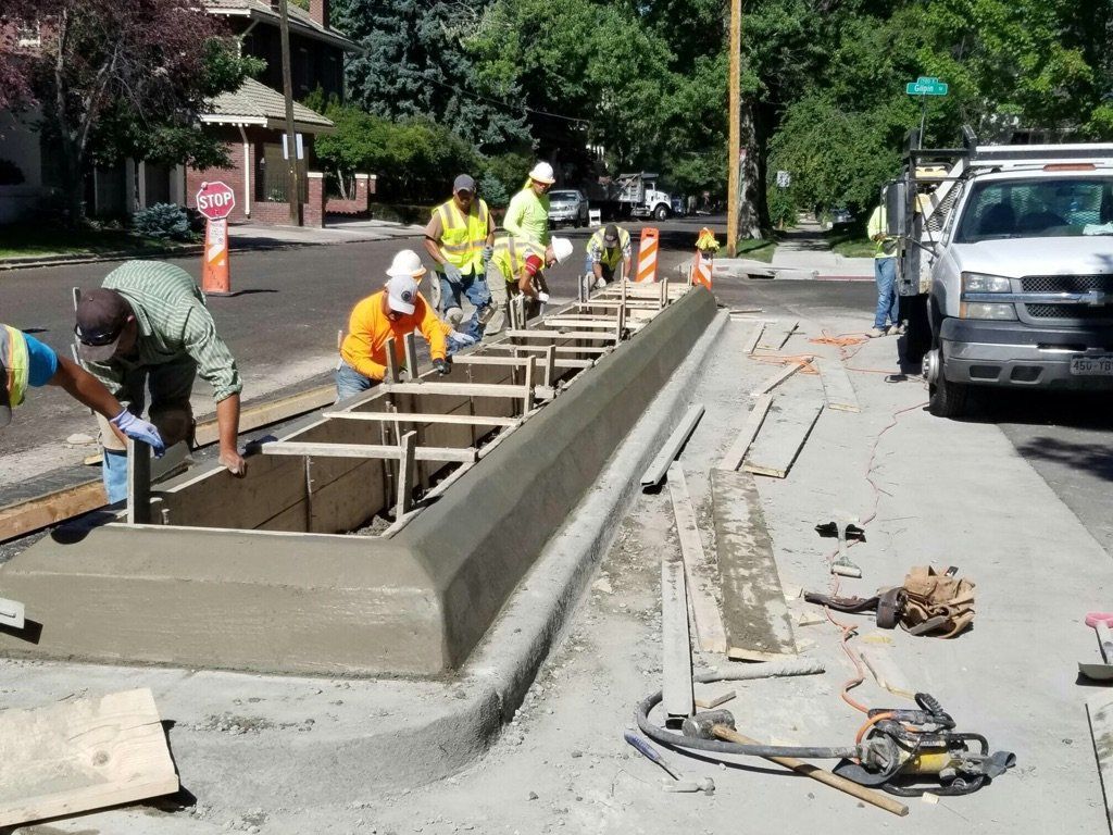 A group of construction workers are working on a sidewalk