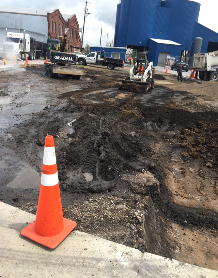 A construction site with a cone and a bulldozer in the background