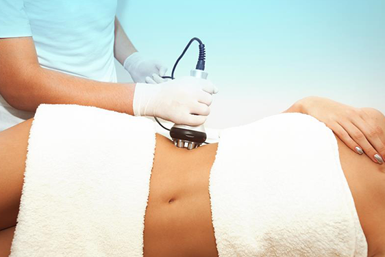 A woman is getting a cavitation treatment on her stomach