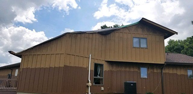 A large brown house with a roof that has been painted.