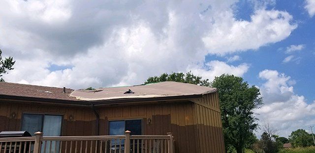 A house with a roof that has been damaged by a storm.