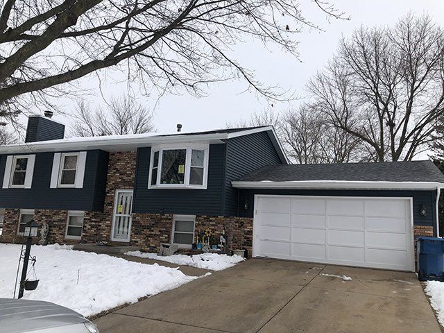A house with a garage and a car parked in front of it.