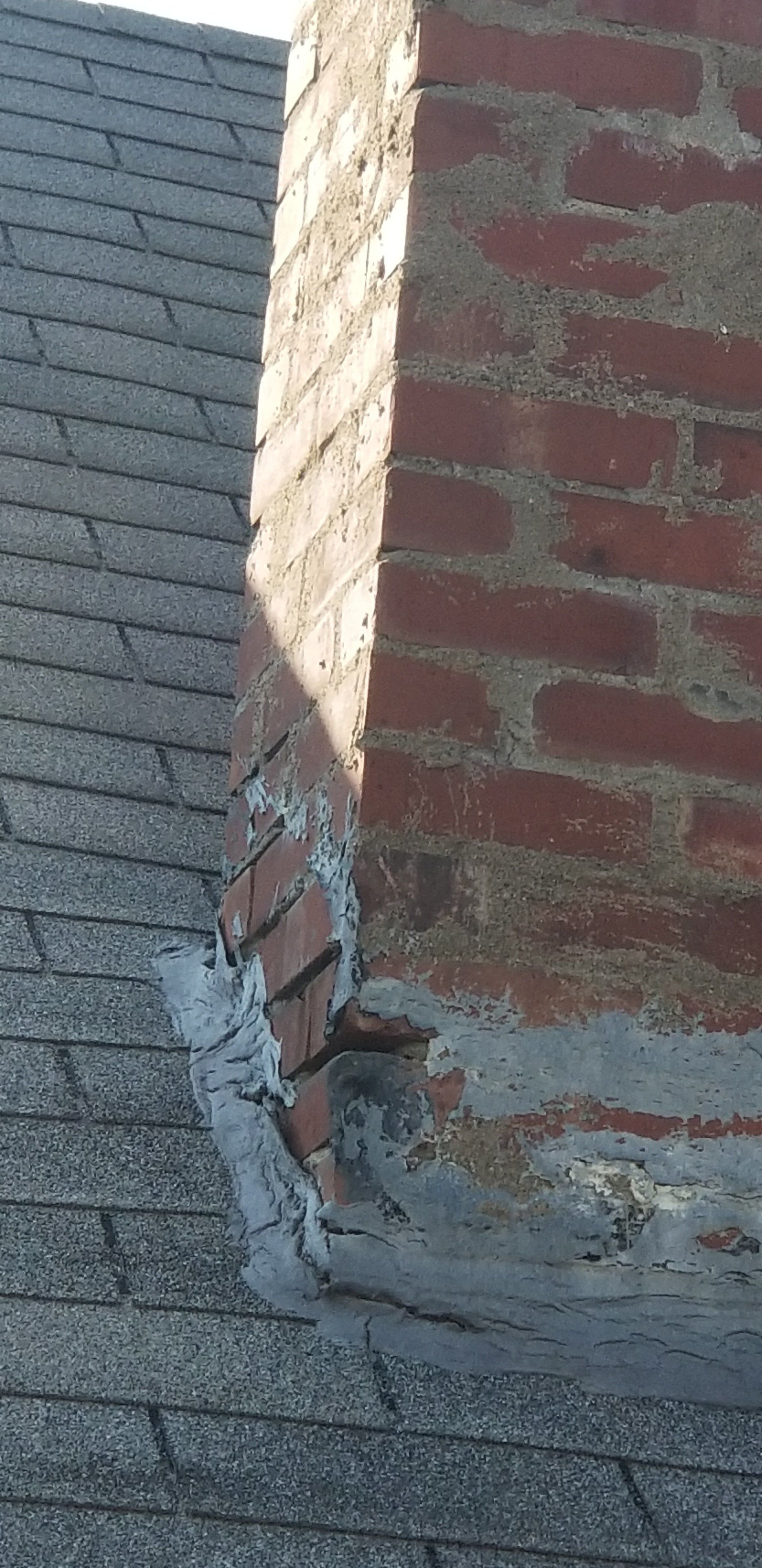A brick chimney is sitting on top of a roof.