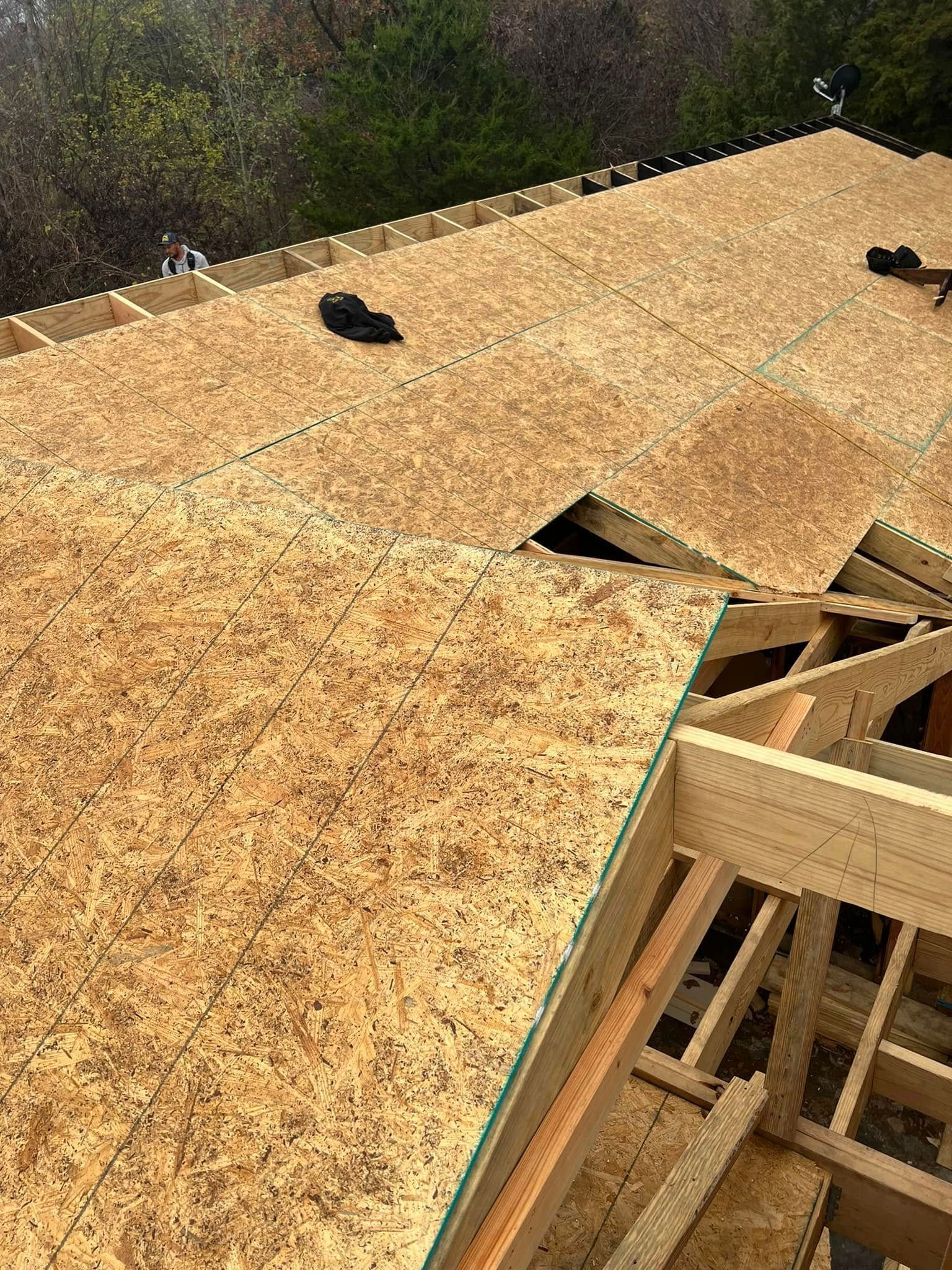 Roof under construction with OSB sheathing and exposed wooden framing.