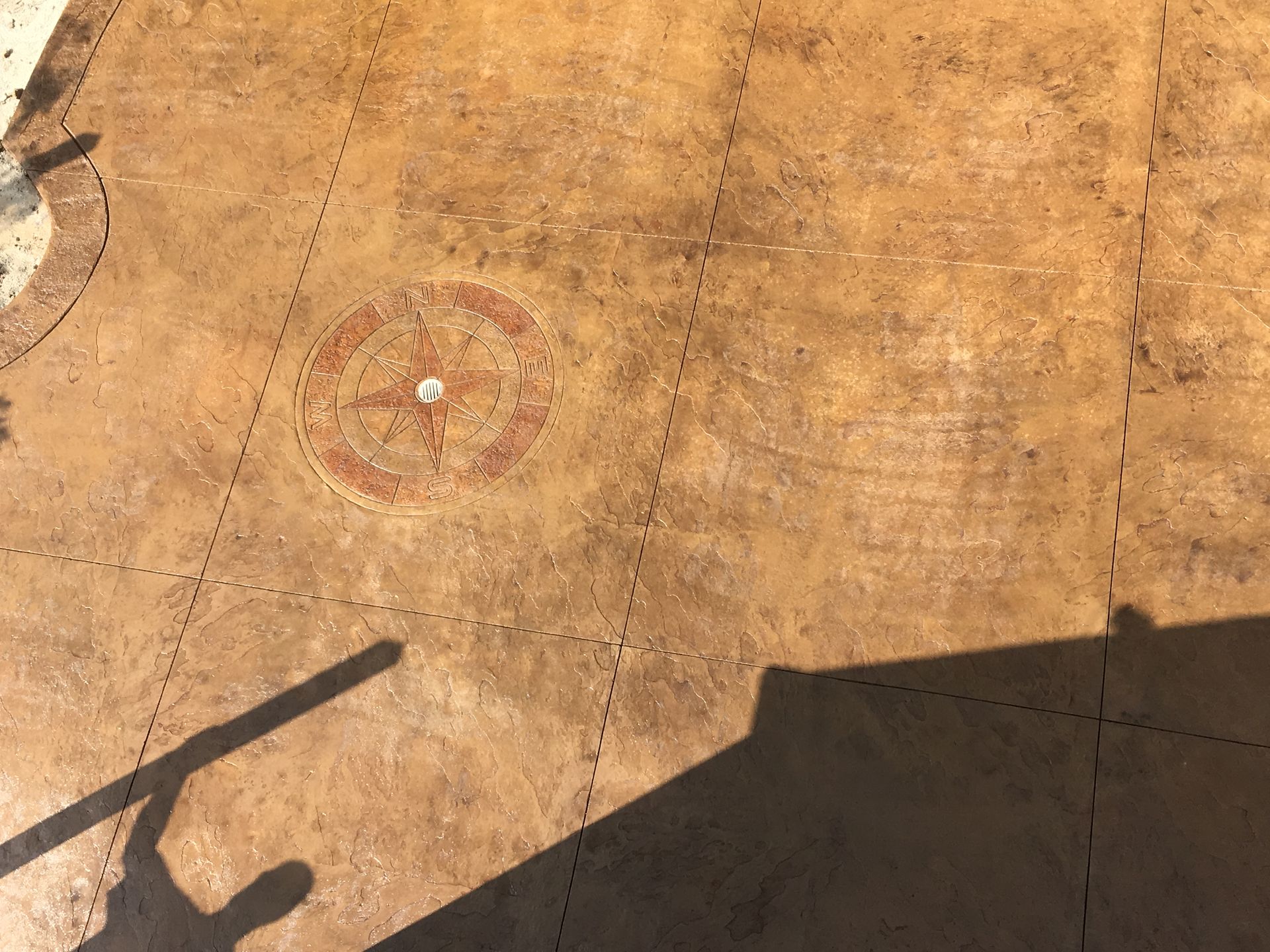 Sandy ground with a circular target marker, a diagonal shadow, and a large building shadow in the corner