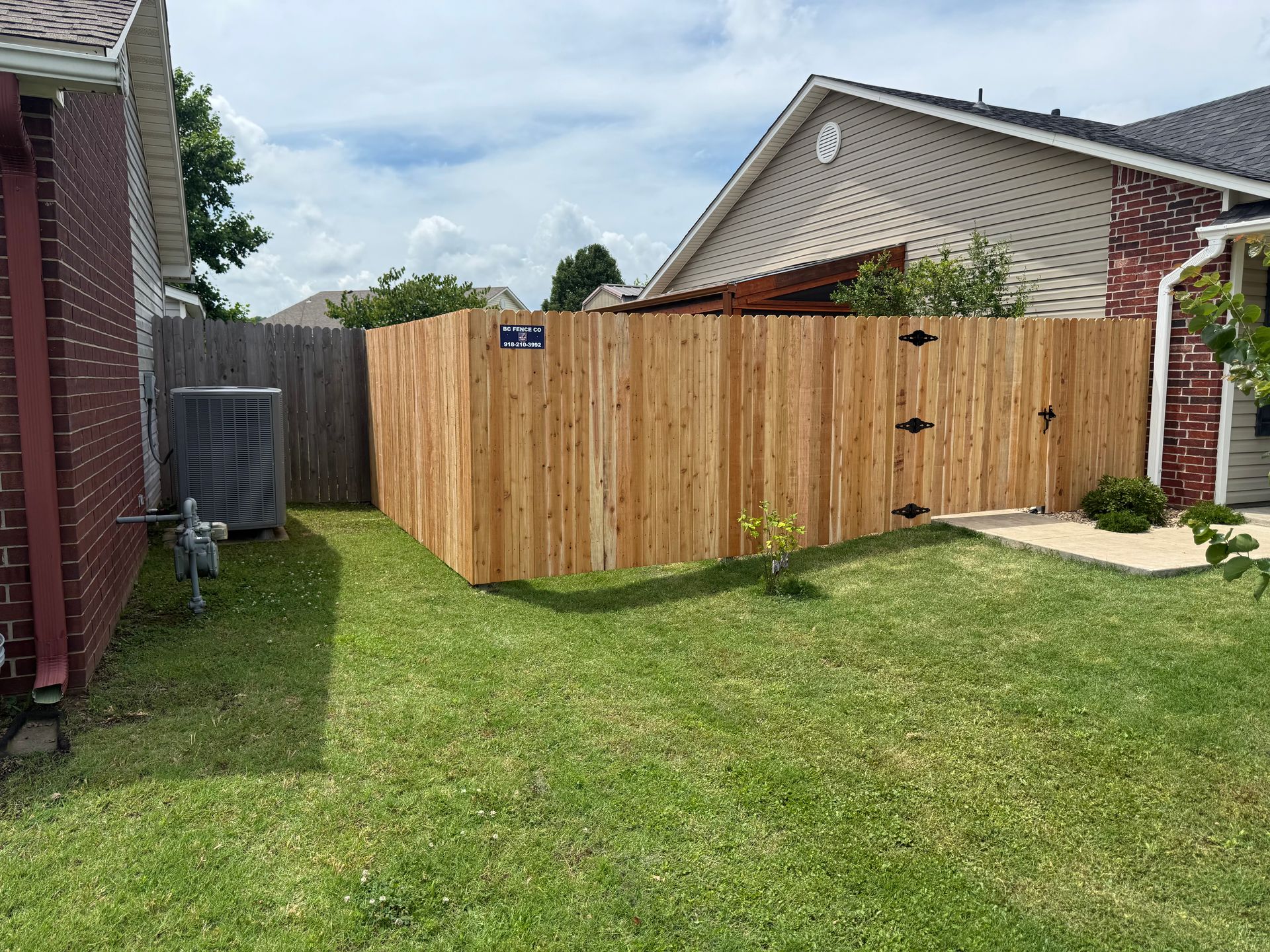 Backyard with new wooden fence beside a lawn and neighboring houses.