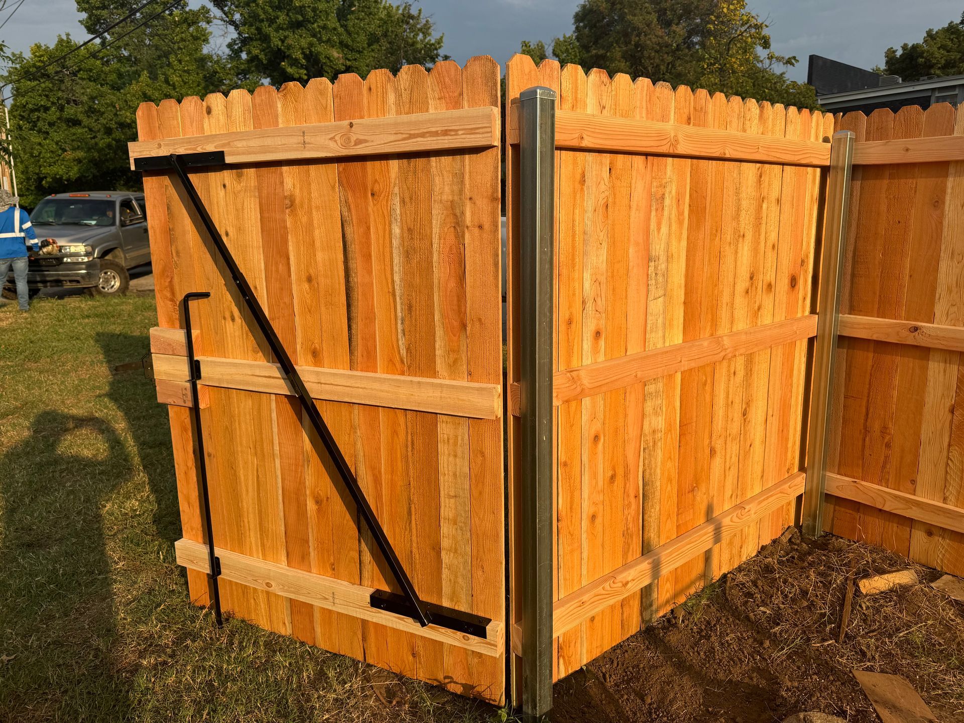 New wooden privacy fence with a diagonal black support brace in a backyard.