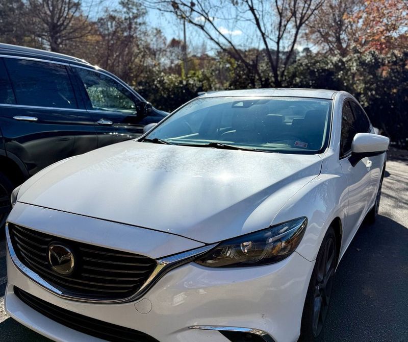 White Mazda 6 sedan parked next to a dark SUV on a sunny day.