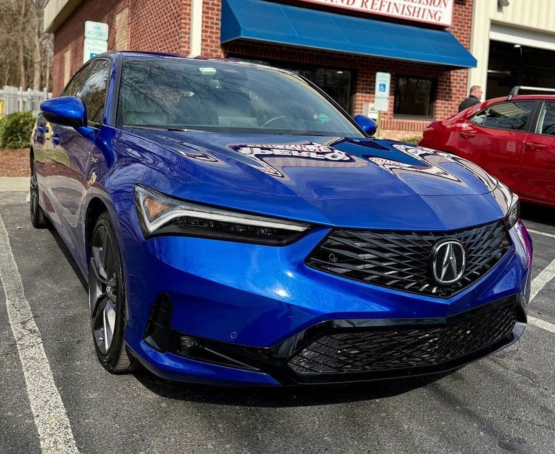 Blue Acura Integra parked in front of a building with a blue awning.