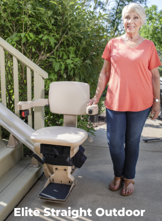 Woman standing beside an outdoor stairlift on a patio, with green plants in the background.