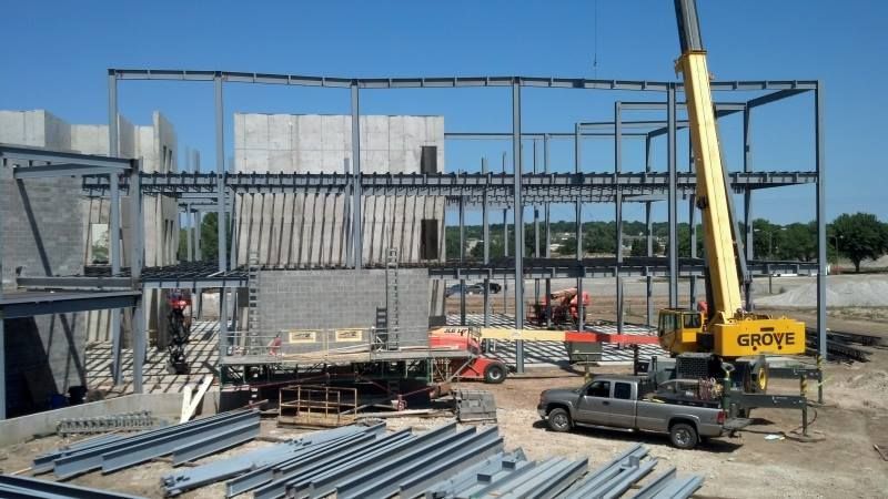 A truck is parked in front of a large building under construction.