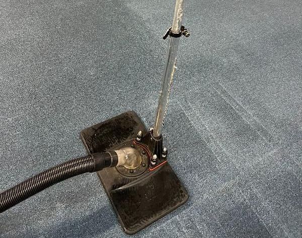 A vacuum cleaner is sitting on top of a blue carpet.