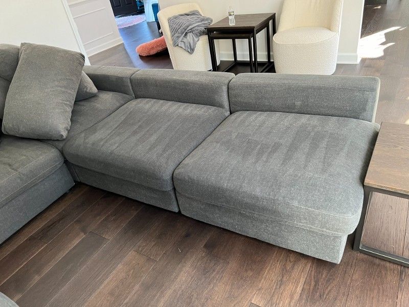 A gray sectional couch is sitting on a wooden floor in a living room.