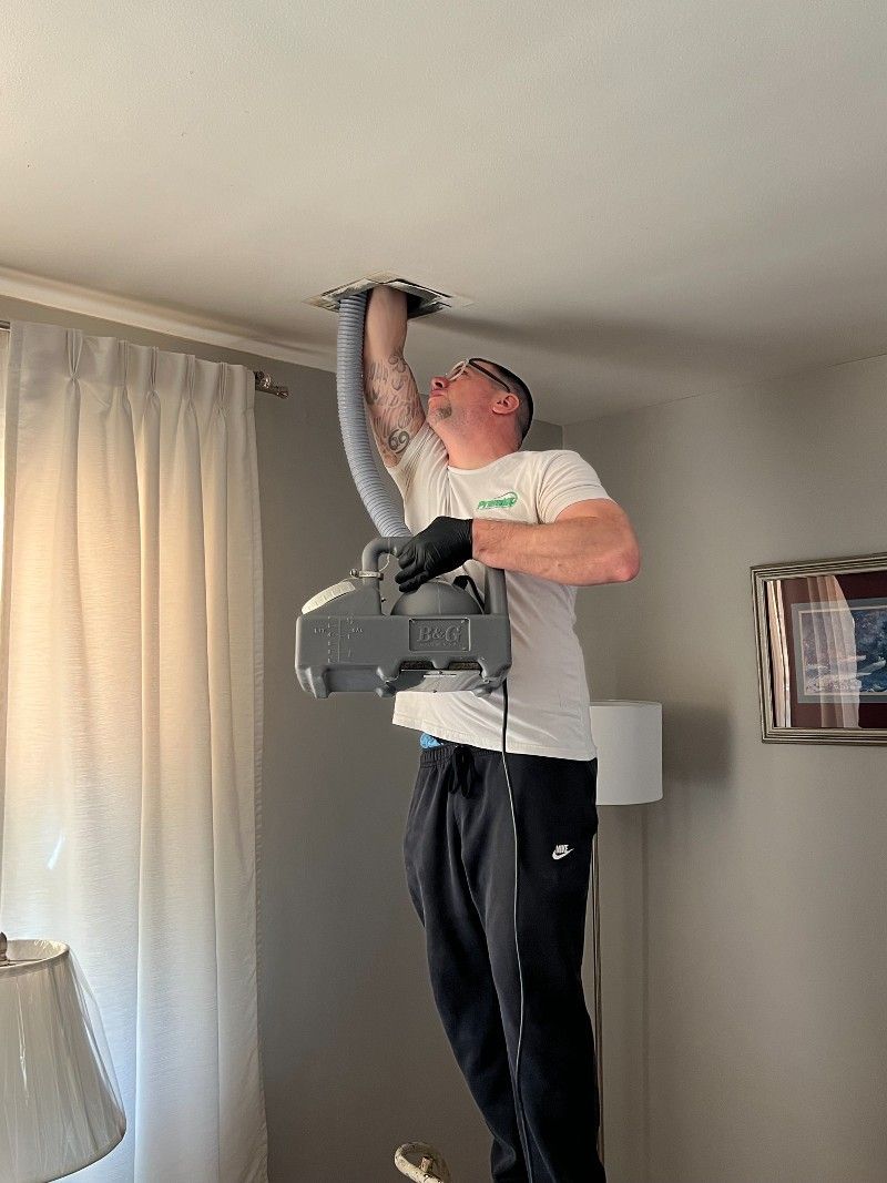 A man is using a vacuum cleaner to clean a ceiling in a living room.