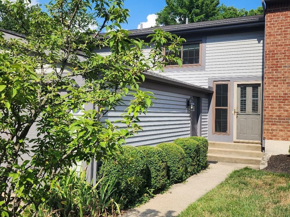 A brick house with a gray siding and a gray door