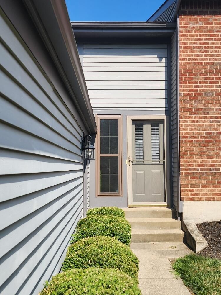 A brick and siding house with a gray door