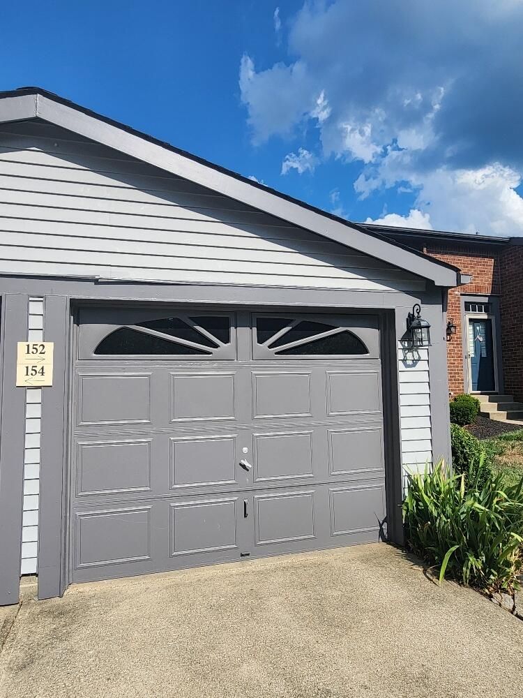 A gray garage door is sitting in front of a house.