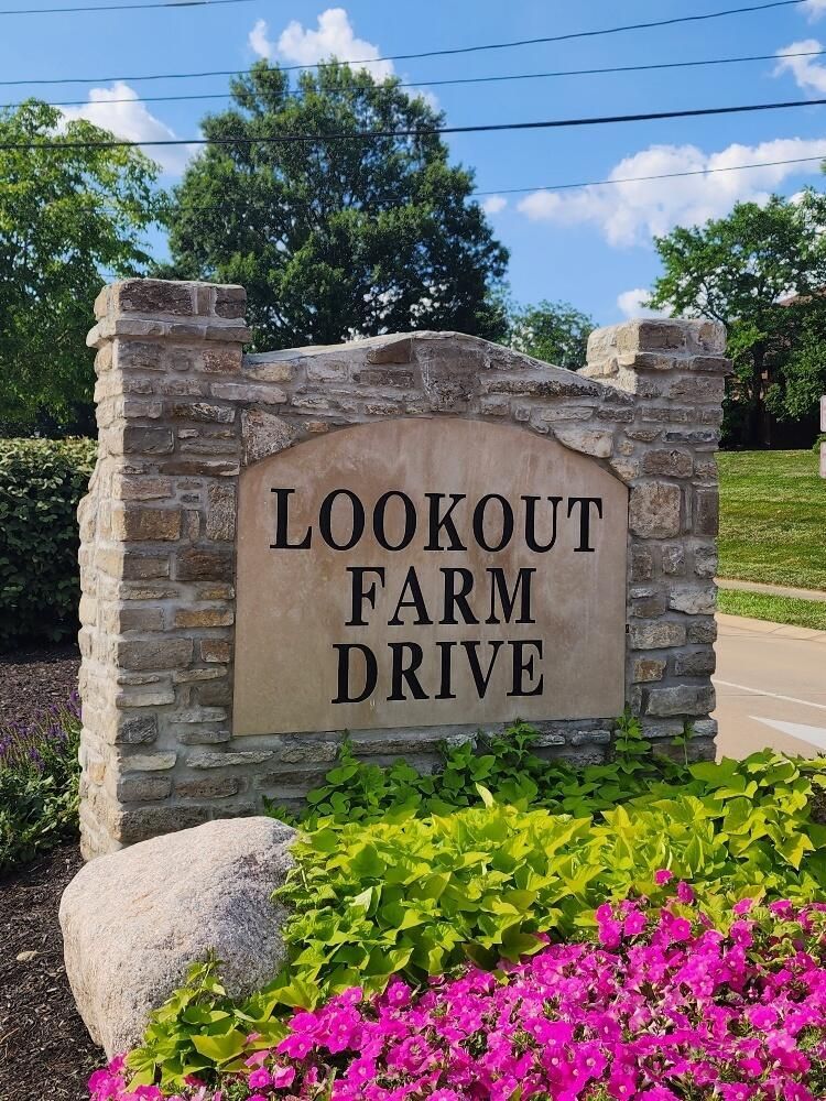 A sign for lookout farm drive is surrounded by pink flowers