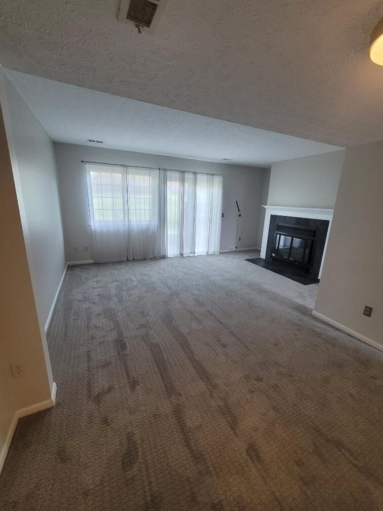 An empty living room with a fireplace and sliding glass doors.