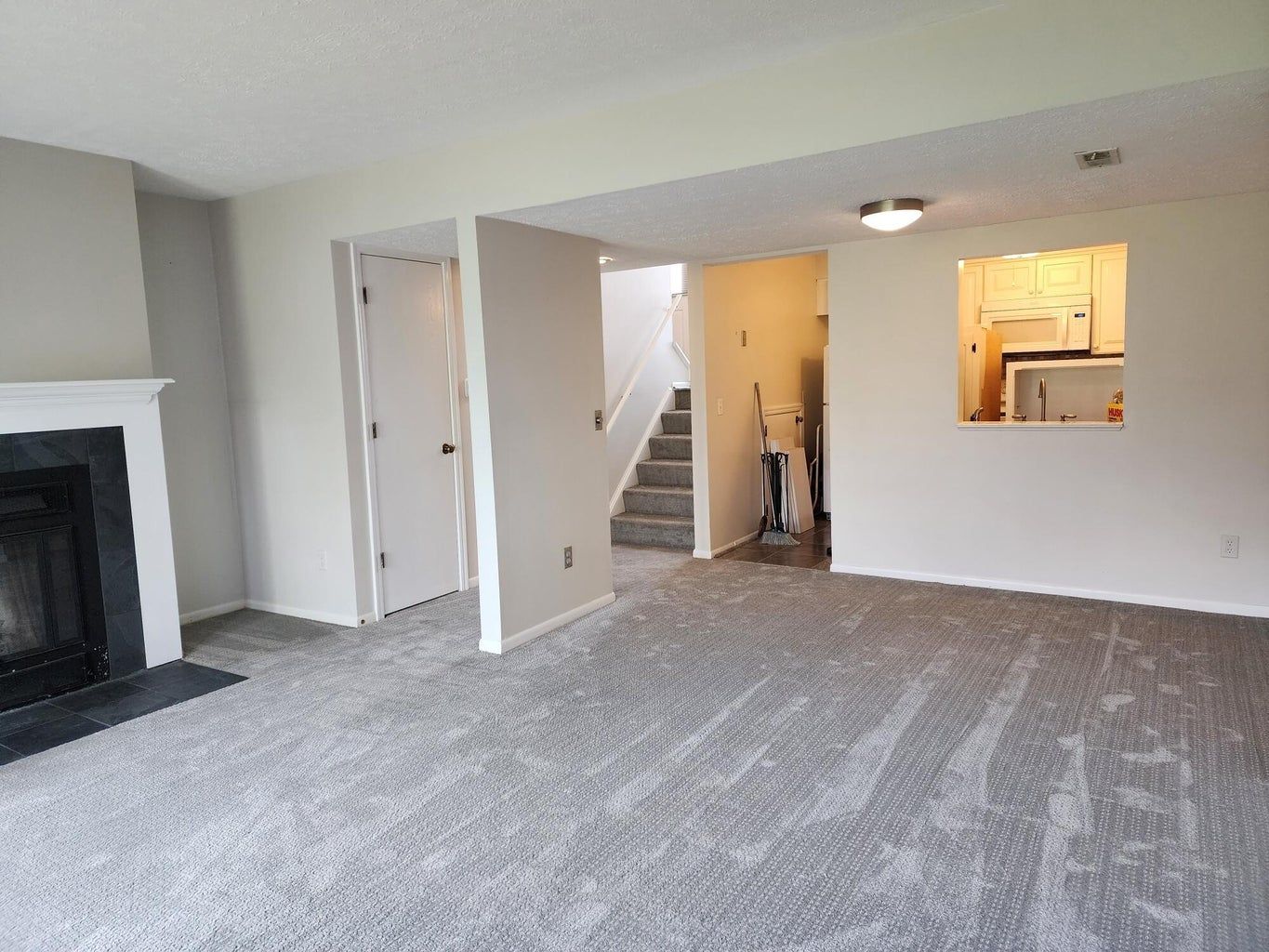 An empty living room with a fireplace and stairs