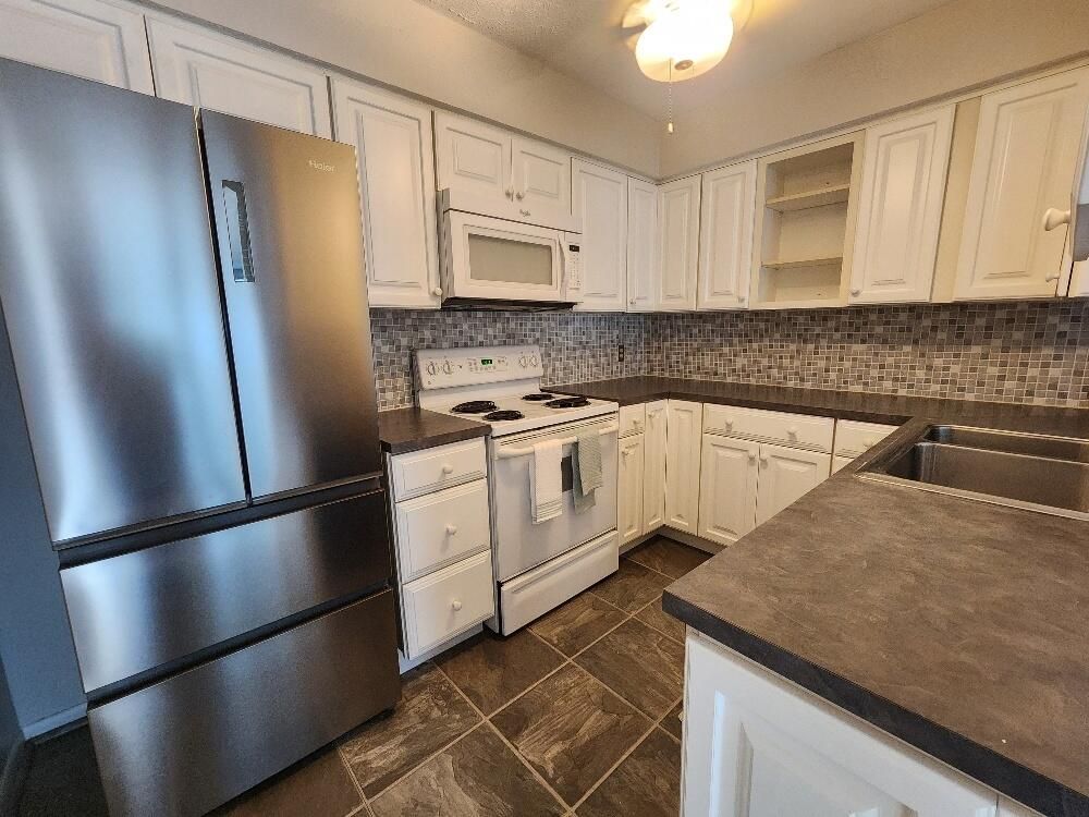 A kitchen with stainless steel appliances and white cabinets.