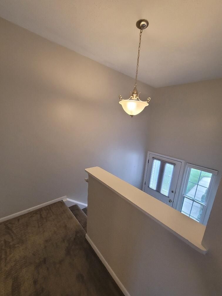 A staircase with a light hanging from the ceiling and a door.