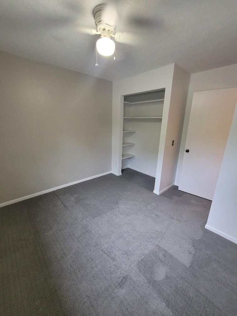 A bedroom with a ceiling fan and a closet.