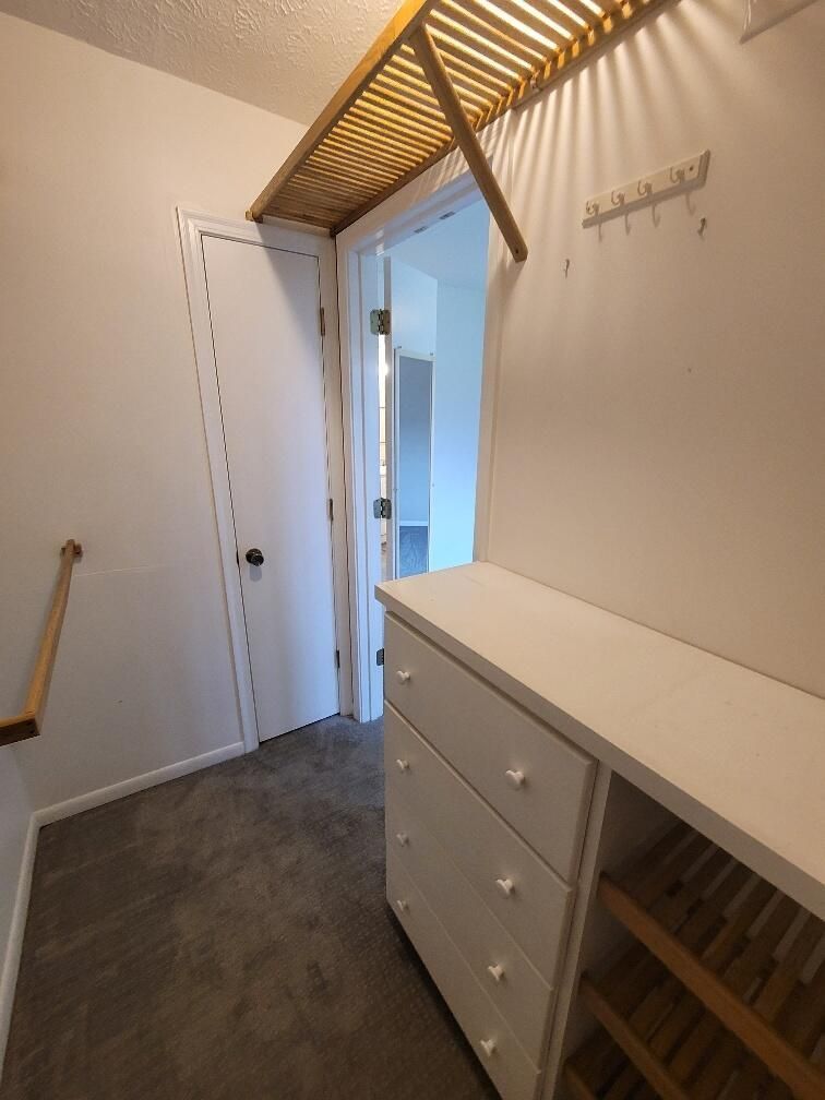 A walk in closet with a wooden shelf and drawers
