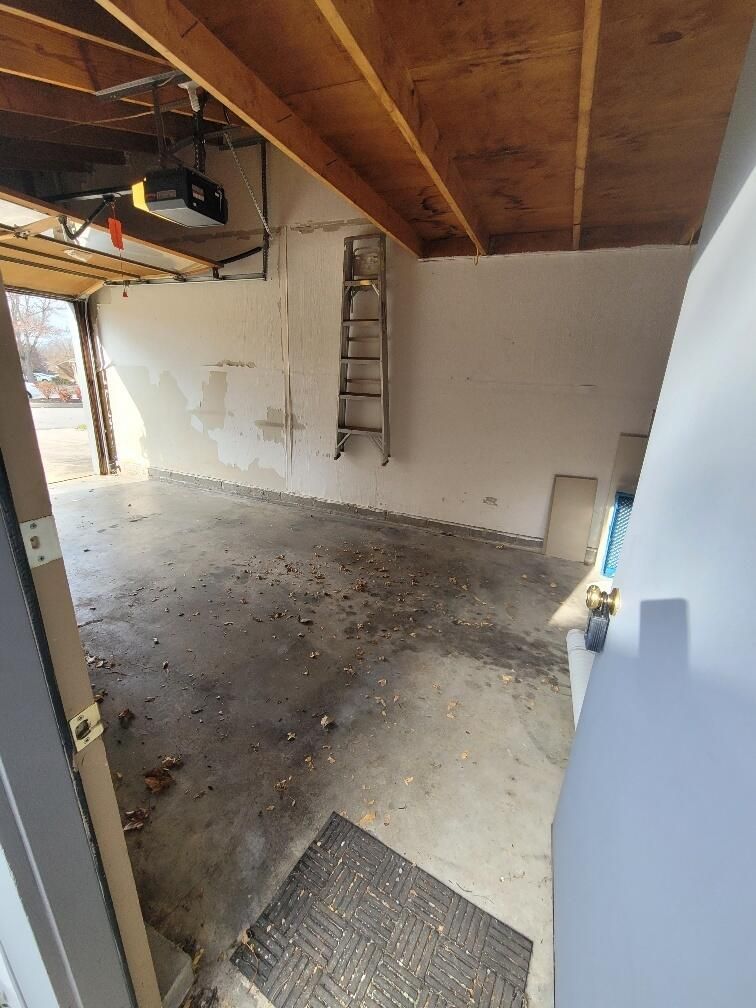 An empty garage with a ladder on the wall and a door