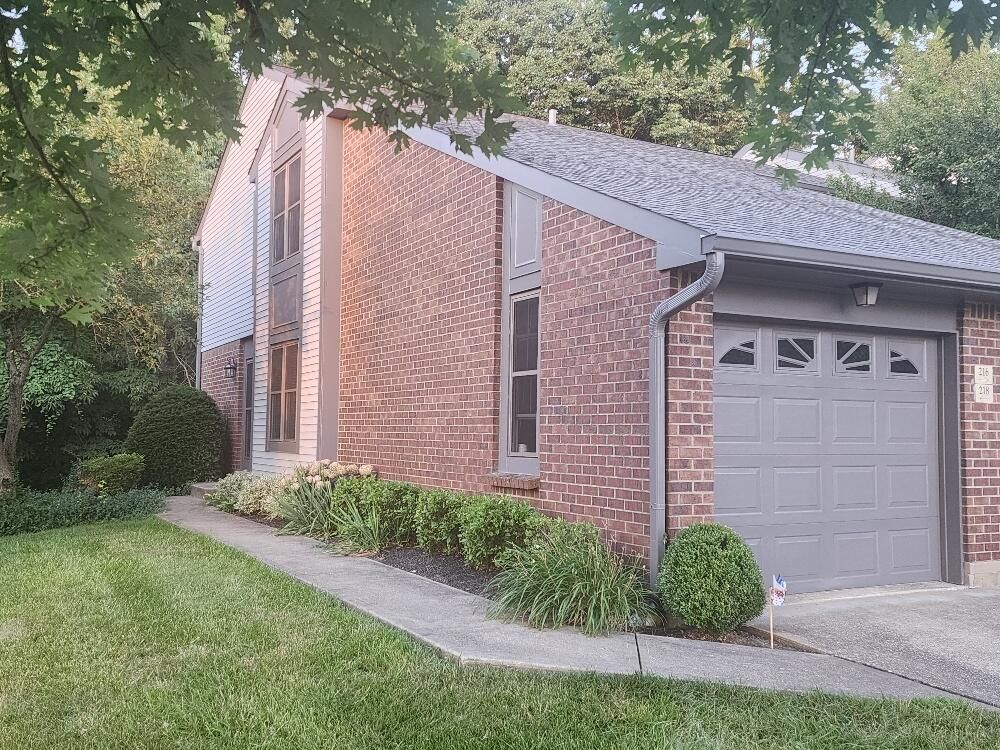 A brick house with a gray garage door and a gray roof.