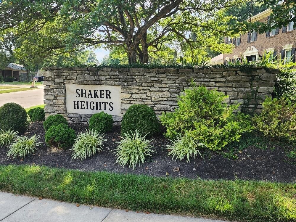 A stone wall with a sign that says shaker heights
