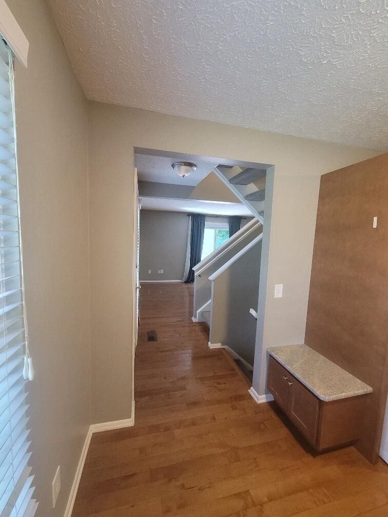A living room with hardwood floors and a staircase leading to the second floor.